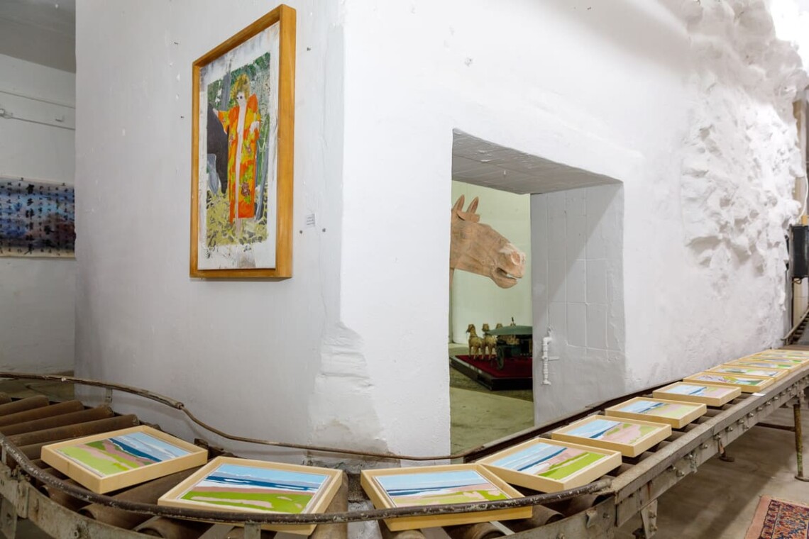 Opere su carta disposte attorno a una colonna, con un dipinto visibile attraverso il passaggio