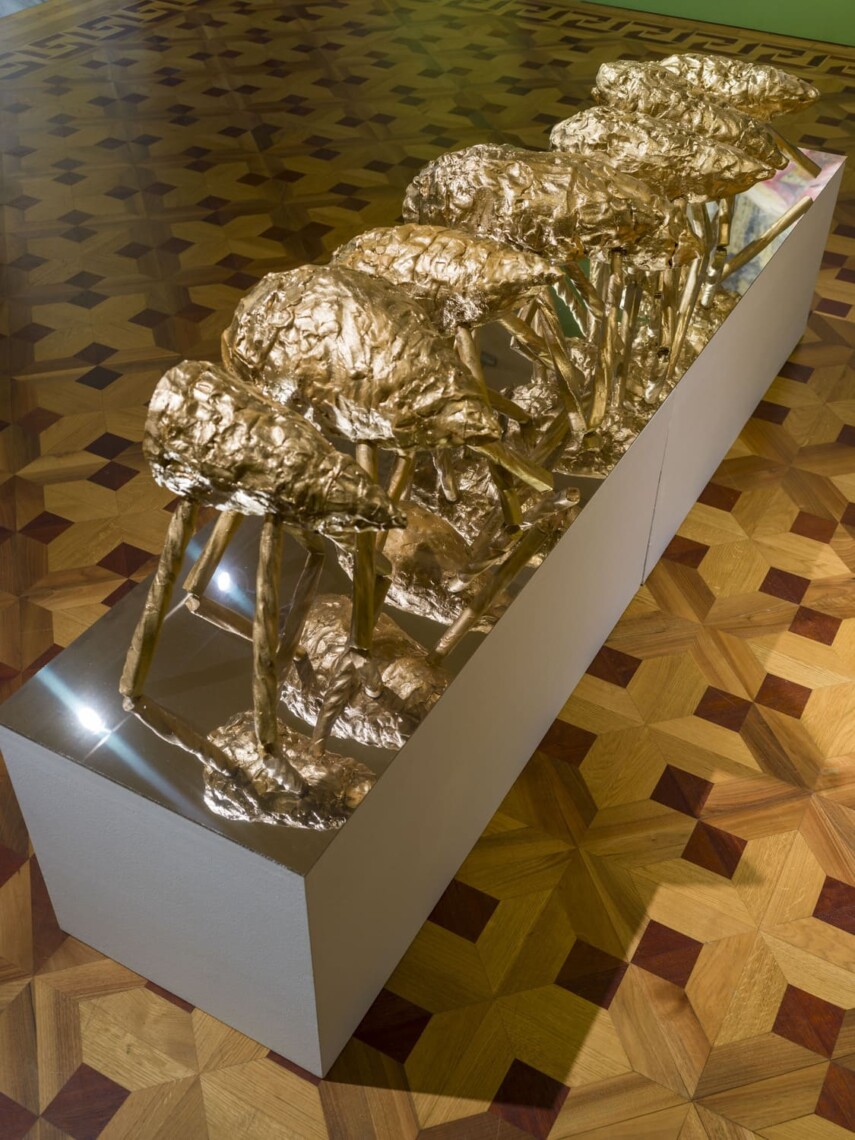 Installazione scultorea dorata di Giuseppe Donnaloia vista dall'alto su parquet intarsiato, mostra Random